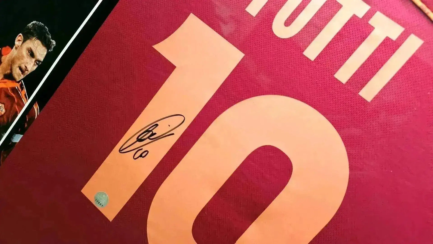View showing signature of Totti above No. 10 on AS Roma shirt in red and yellow.