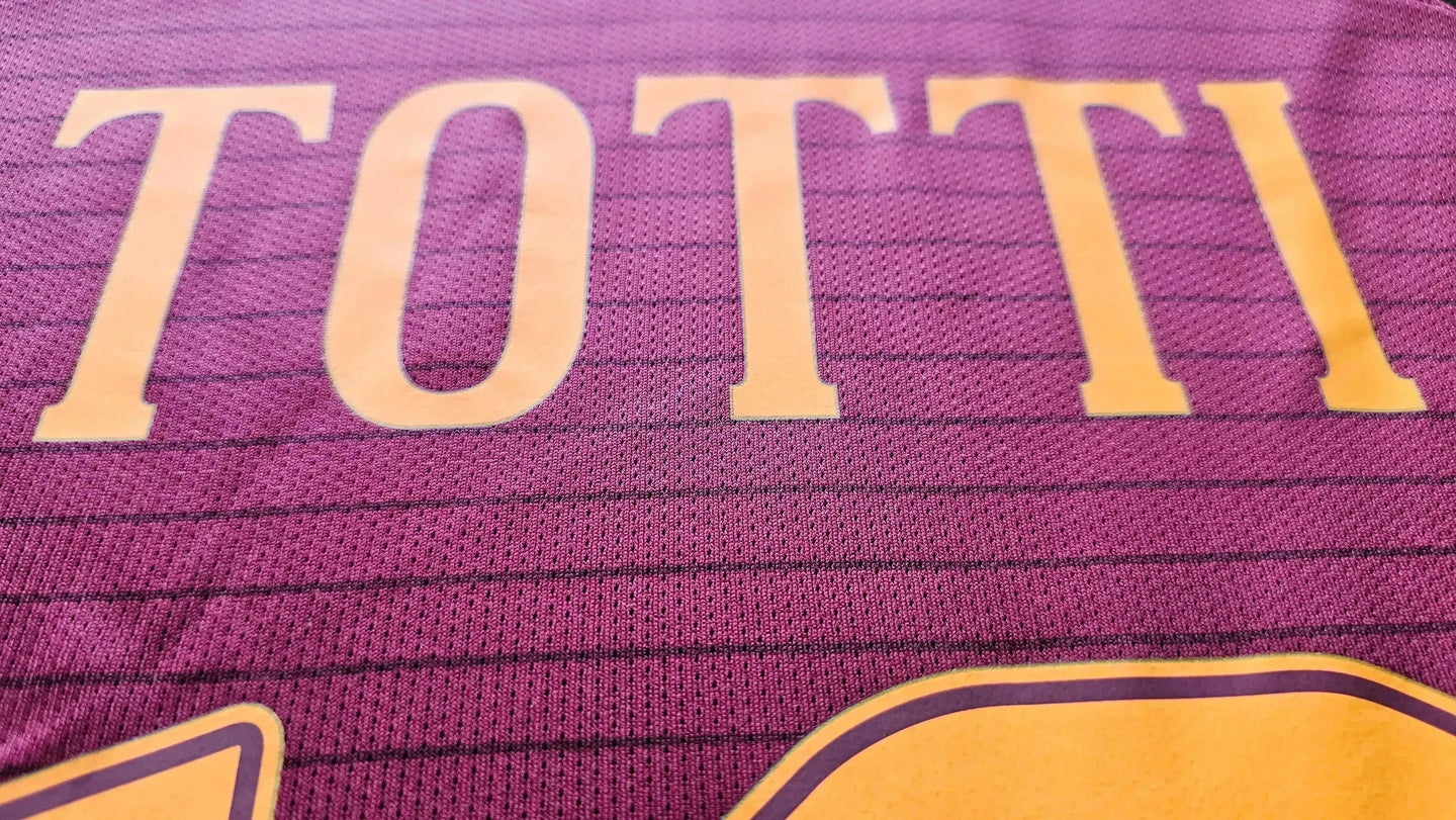 Close-up detail showing the name 'TOTTI' on the back of the football shirt in orange lettering.