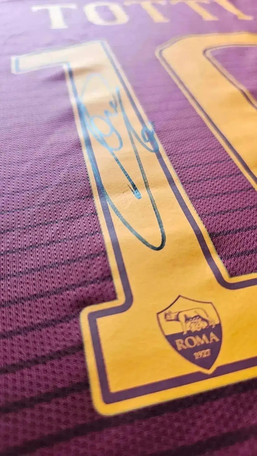 Close-up of shirt detail showing No. 10, name 'TOTTI', and signature on A.S. Roma shirt.