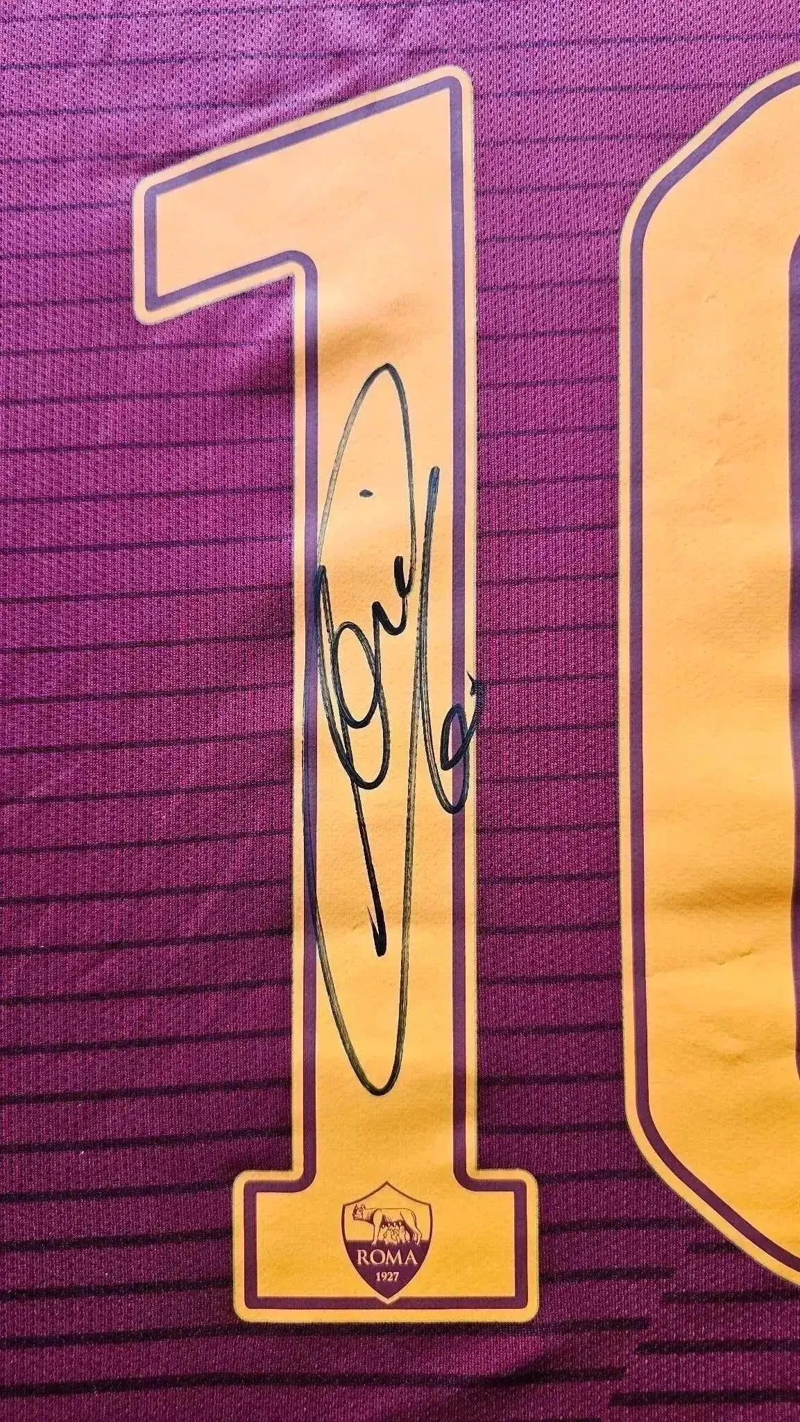 Back view showing No. 10 and a signature on a red football shirt with A.S. Roma crest.