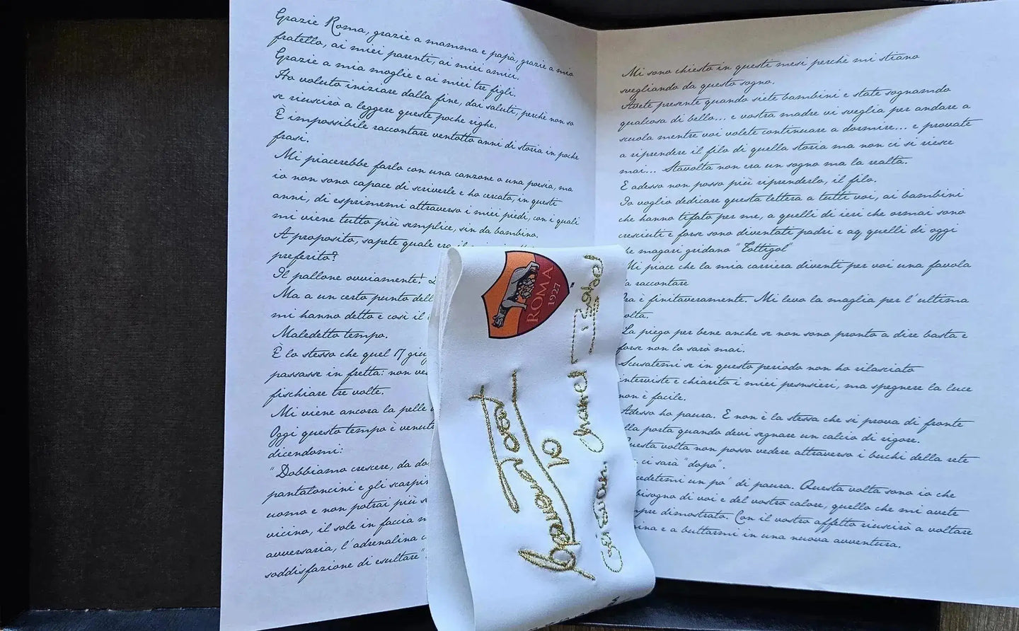 Francesco Totti signed captains band with A.S. Roma crest and handwritten booklet in background.