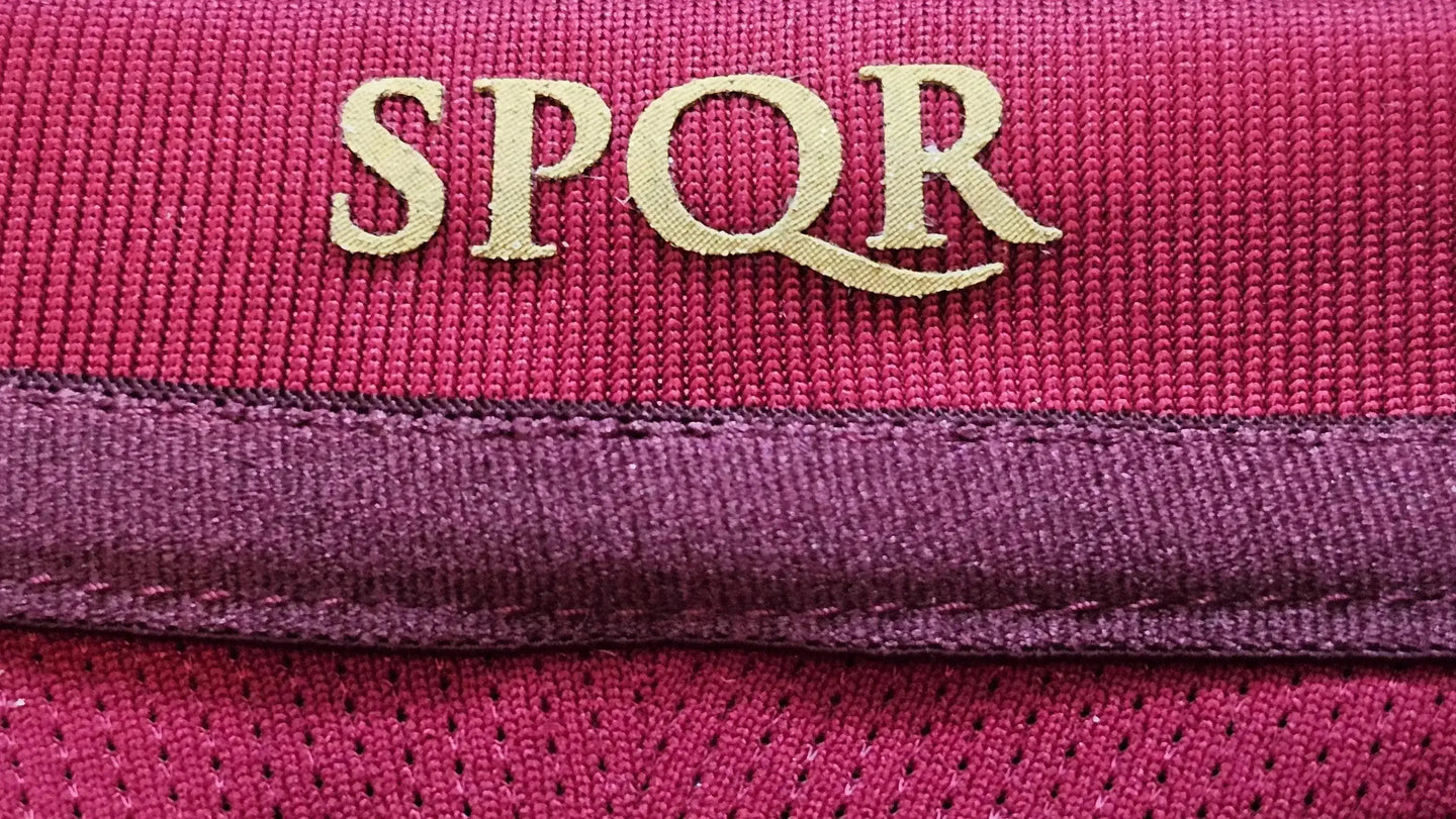 Close-up showing the gold 'SPQR' emblem on the upper part of a Roma shirt.