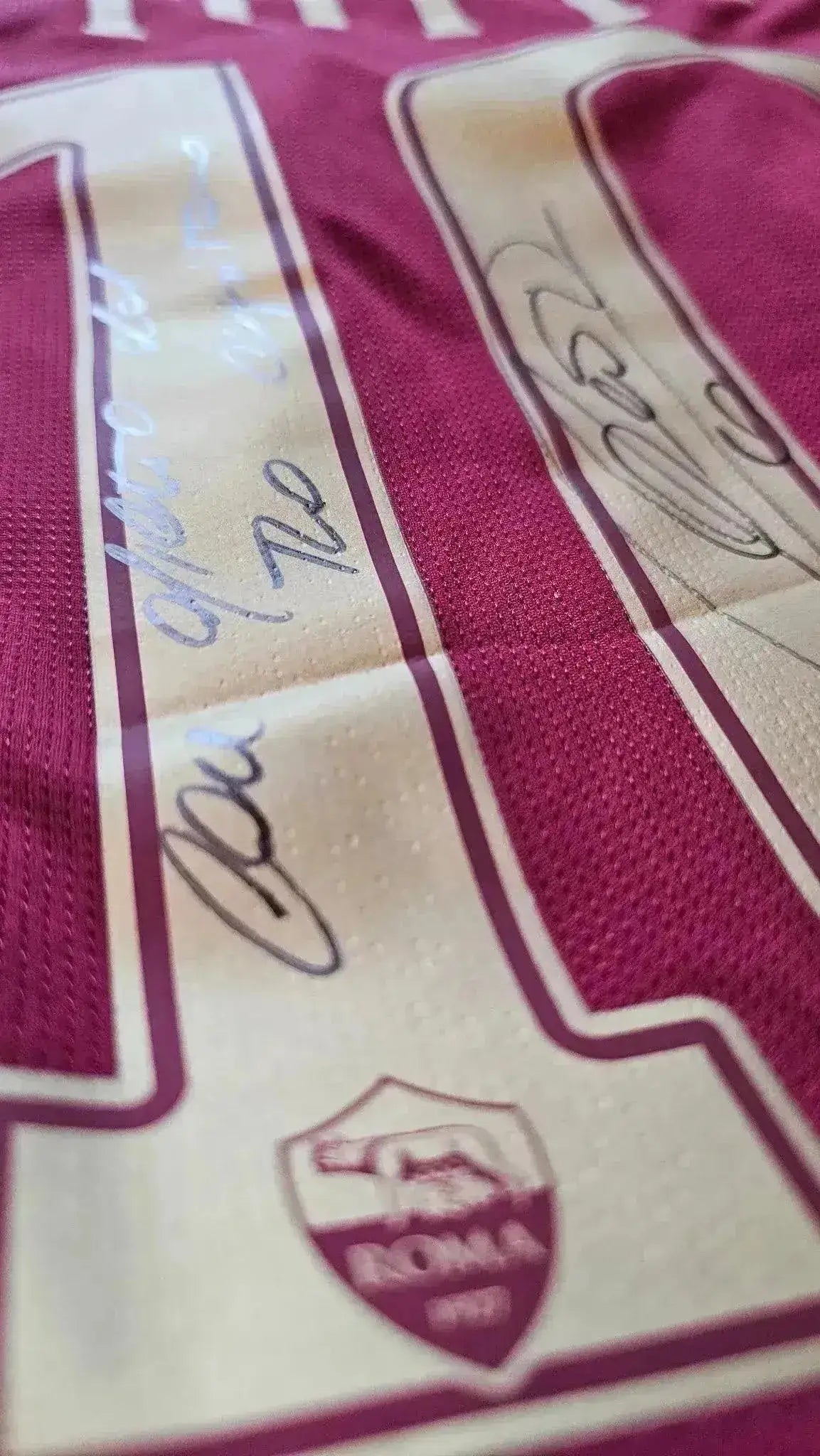 Close-up of the A.S. Roma shirt showing No. 10, with visible signatures and club crest.
