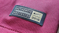 Close-up of size tag showing 'AUTHENTIC', 'X8D768098', and Nike logo, on maroon fabric.