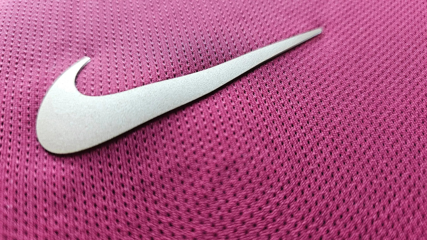 Close-up of the Nike logo on a pink texture, revealing signature detail of the shirt.
