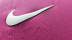 Close-up of the Nike logo on a pink texture, revealing signature detail of the shirt.