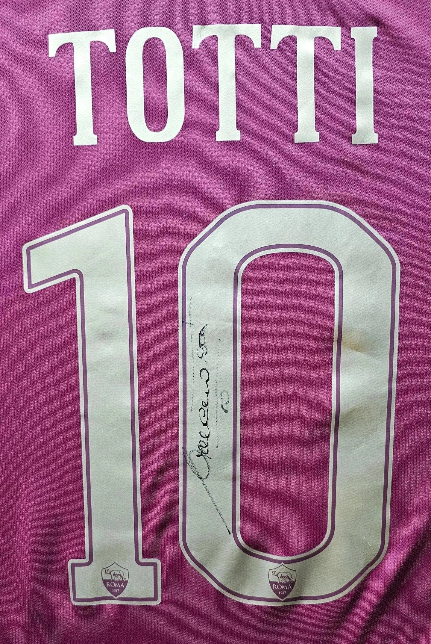 Back view featuring signature and No. 10 on a pink Francesco Totti Roma shirt with club crest.