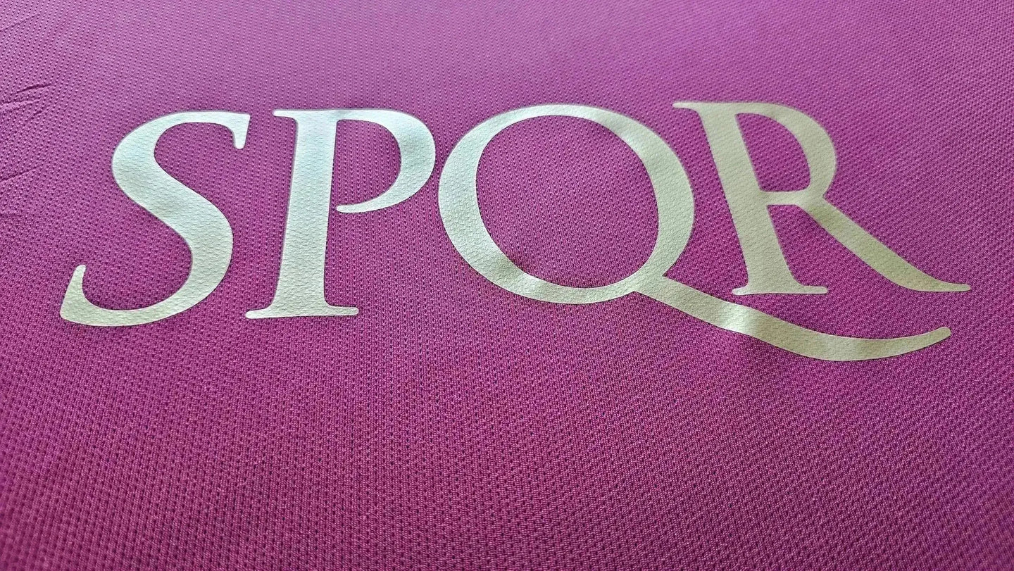Close-up of the SPQR detail on a signed match shirt in pink fabric.