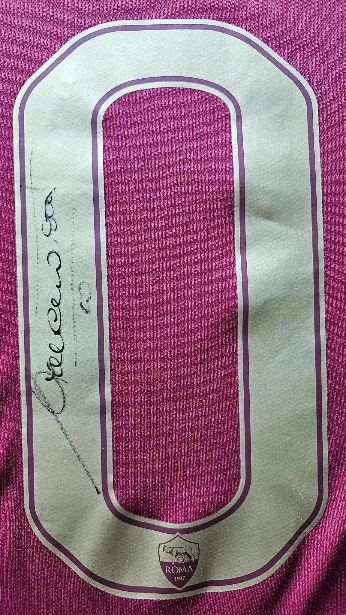 Close-up of signature detail on Francesco Totti's No. 10 Roma shirt, featuring a pink number and crest.