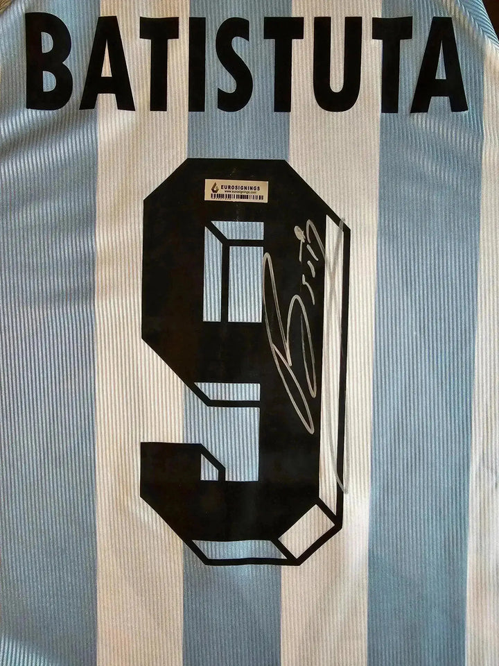 Back view showing Batistuta, No. 9, and a visible signature on a blue and white striped soccer jersey.
