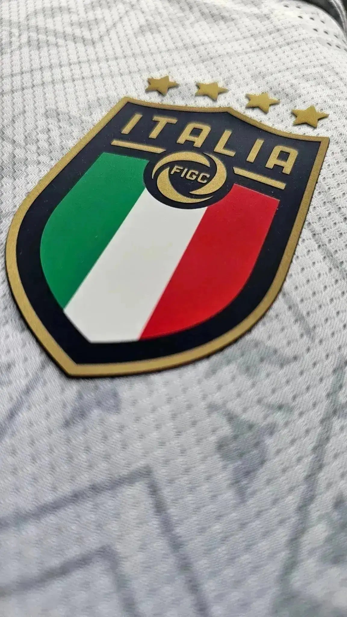 Italia crest with three stars and green, white, and red colors on a football shirt.
