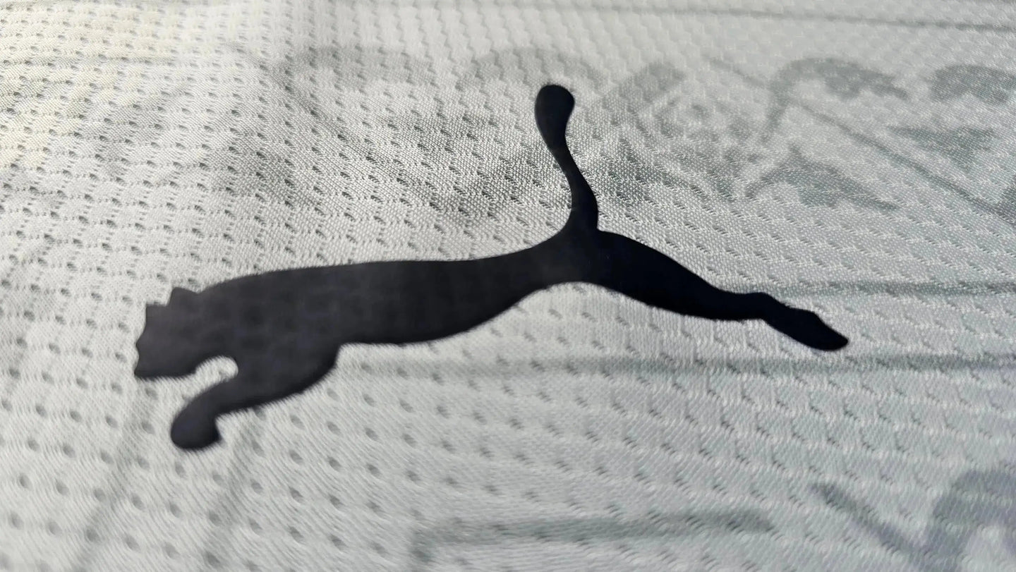 Close-up view of the black Puma logo on a white football shirt texture.