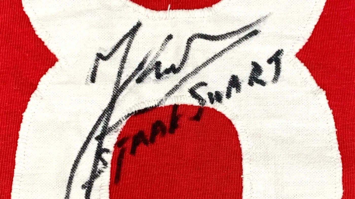 Textured patch with "SJAAK SWART" signature on a red and white Ajax football shirt.