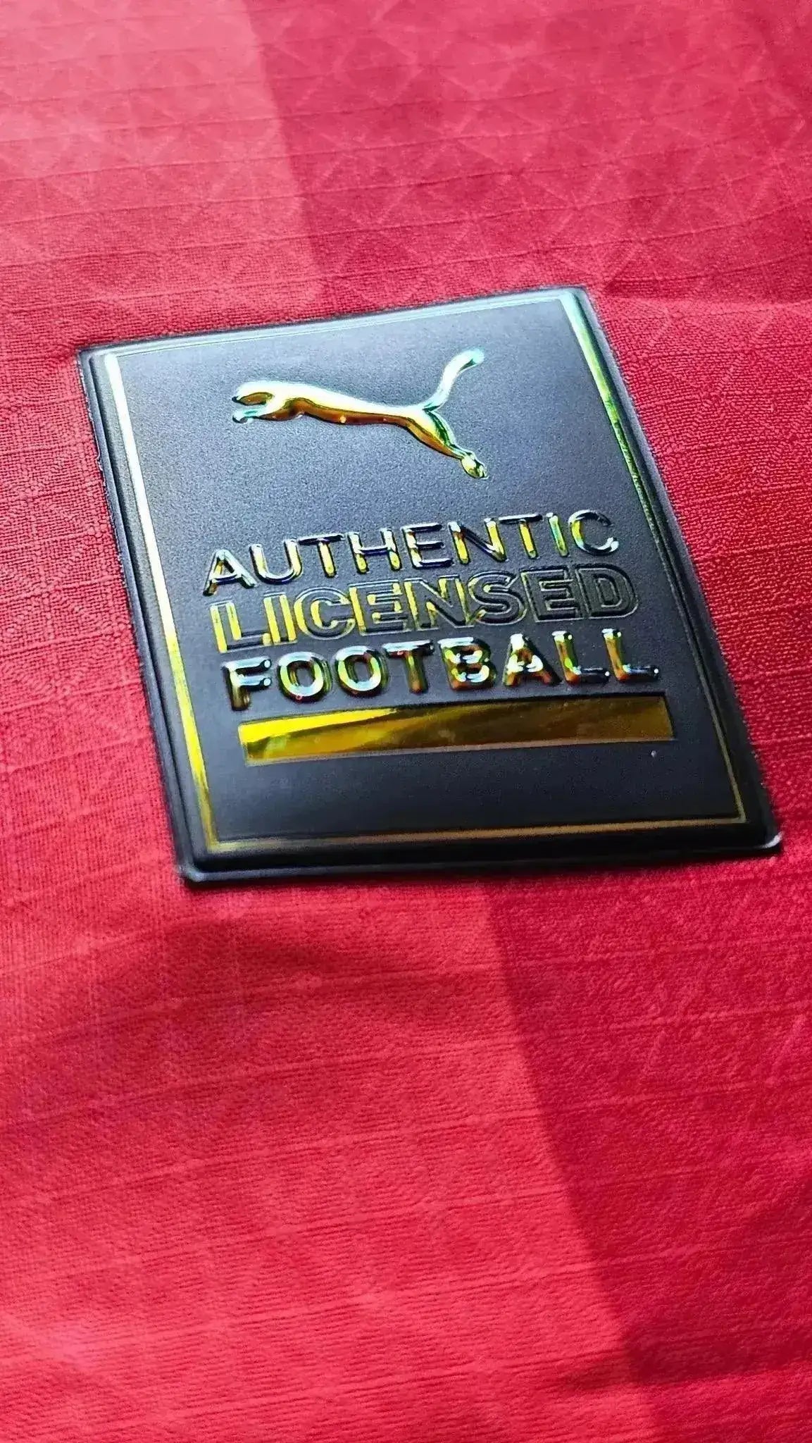 Close-up of crest detail showing 'AUTHENTIC LICENSED FOOTBALL' and Puma logo.