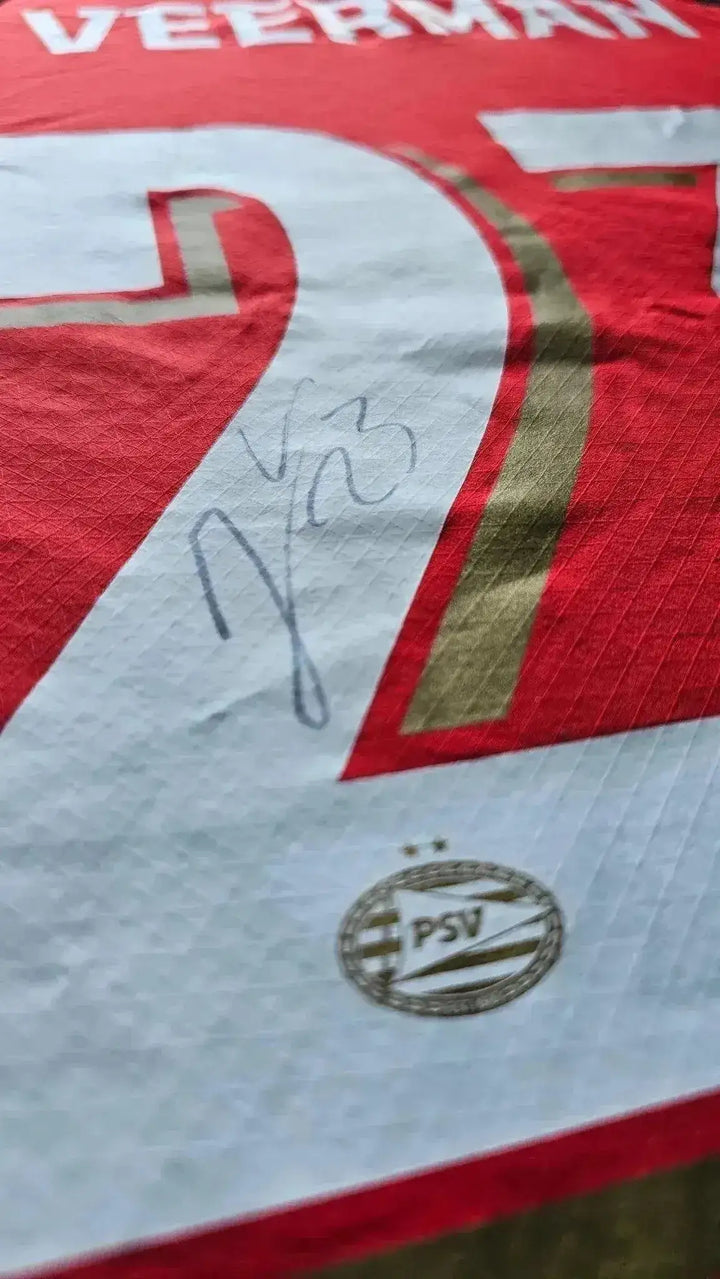 Close-up of signature on No. 23 Joey Veerman PSV football shirt with PSV crest detail.