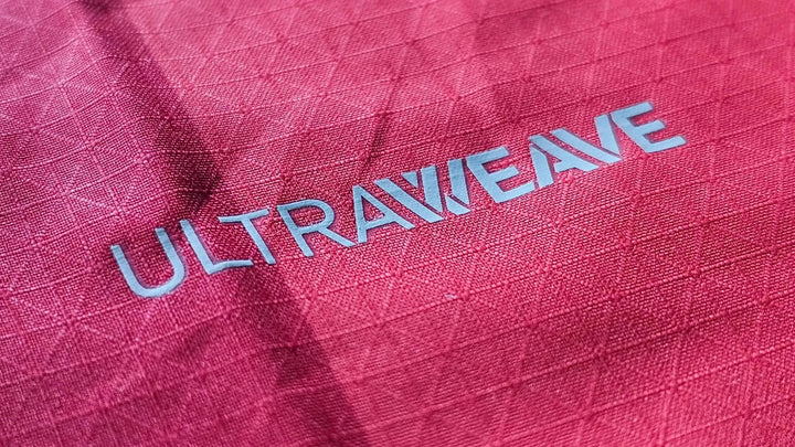 Close-up of the Ultraweave text on a red football shirt fabric, highlighting its texture.