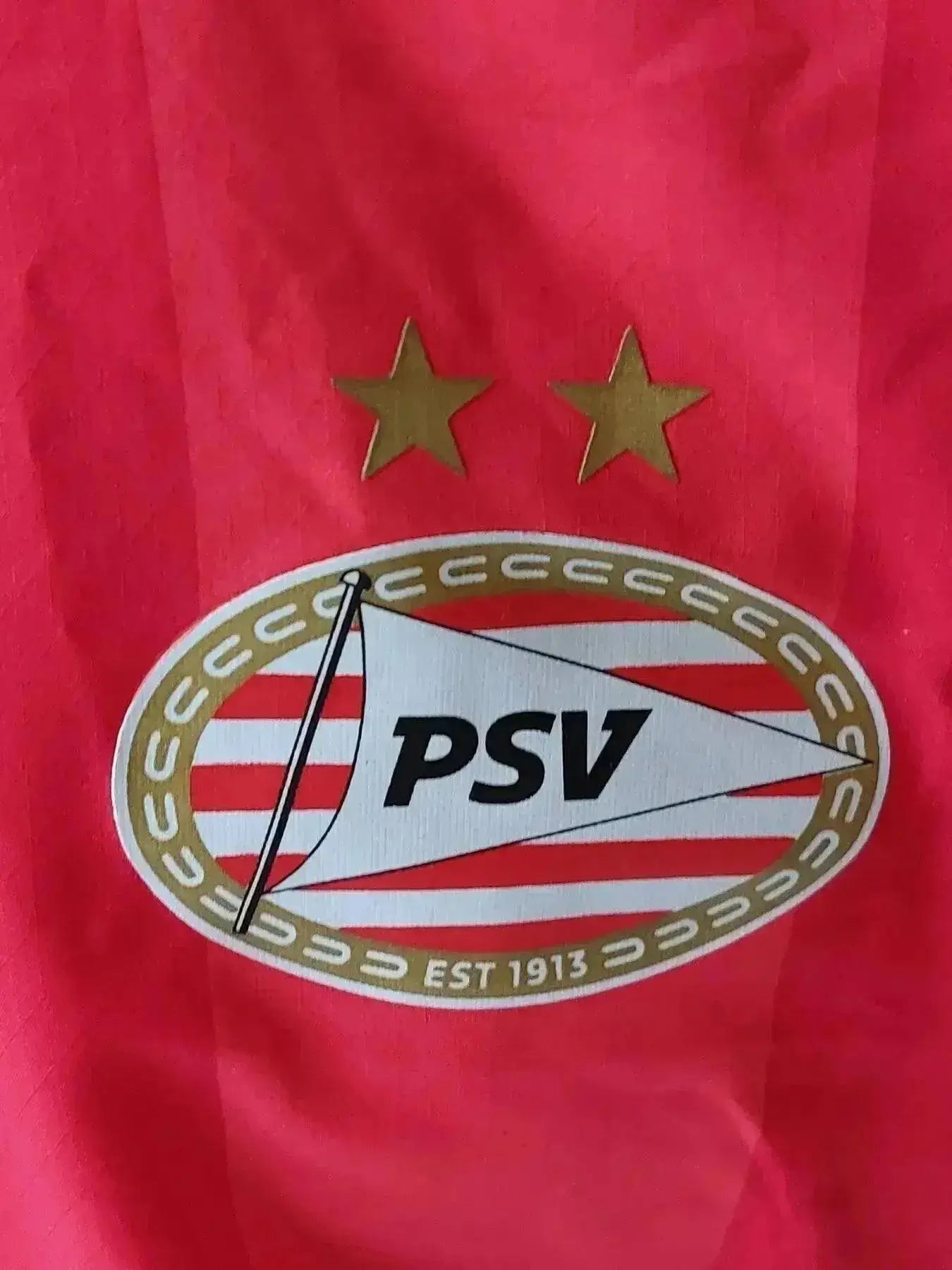 PSV Eindhoven crest featuring two gold stars and the word PSV in the center.
