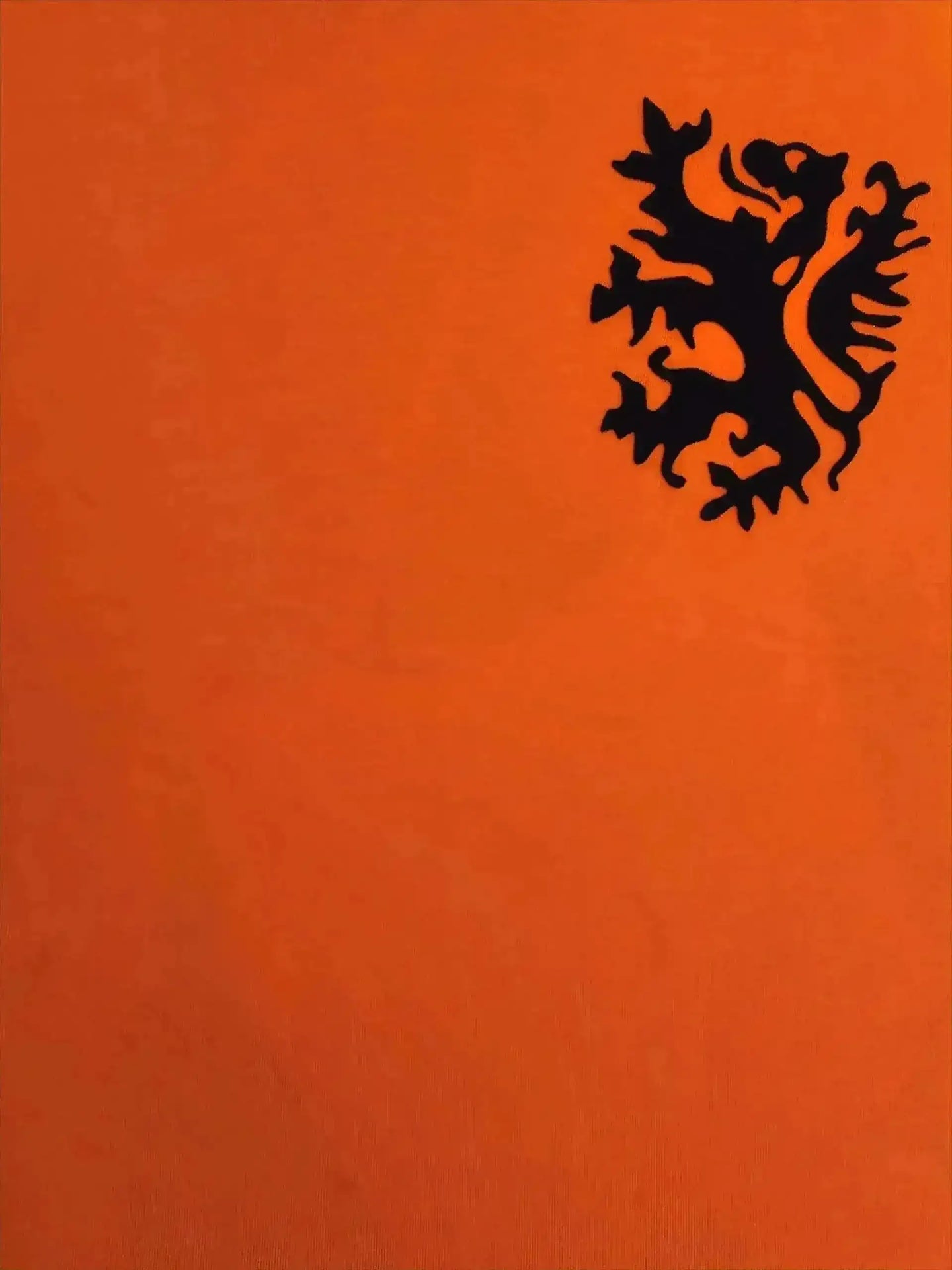 Black lion crest detail on vibrant orange background of Holland football shirt.