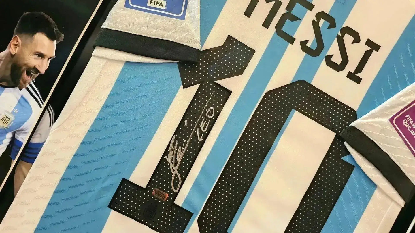 Close-up of Messi's No. 10 signed on Argentina soccer jersey, featuring FIFA badge and crest.