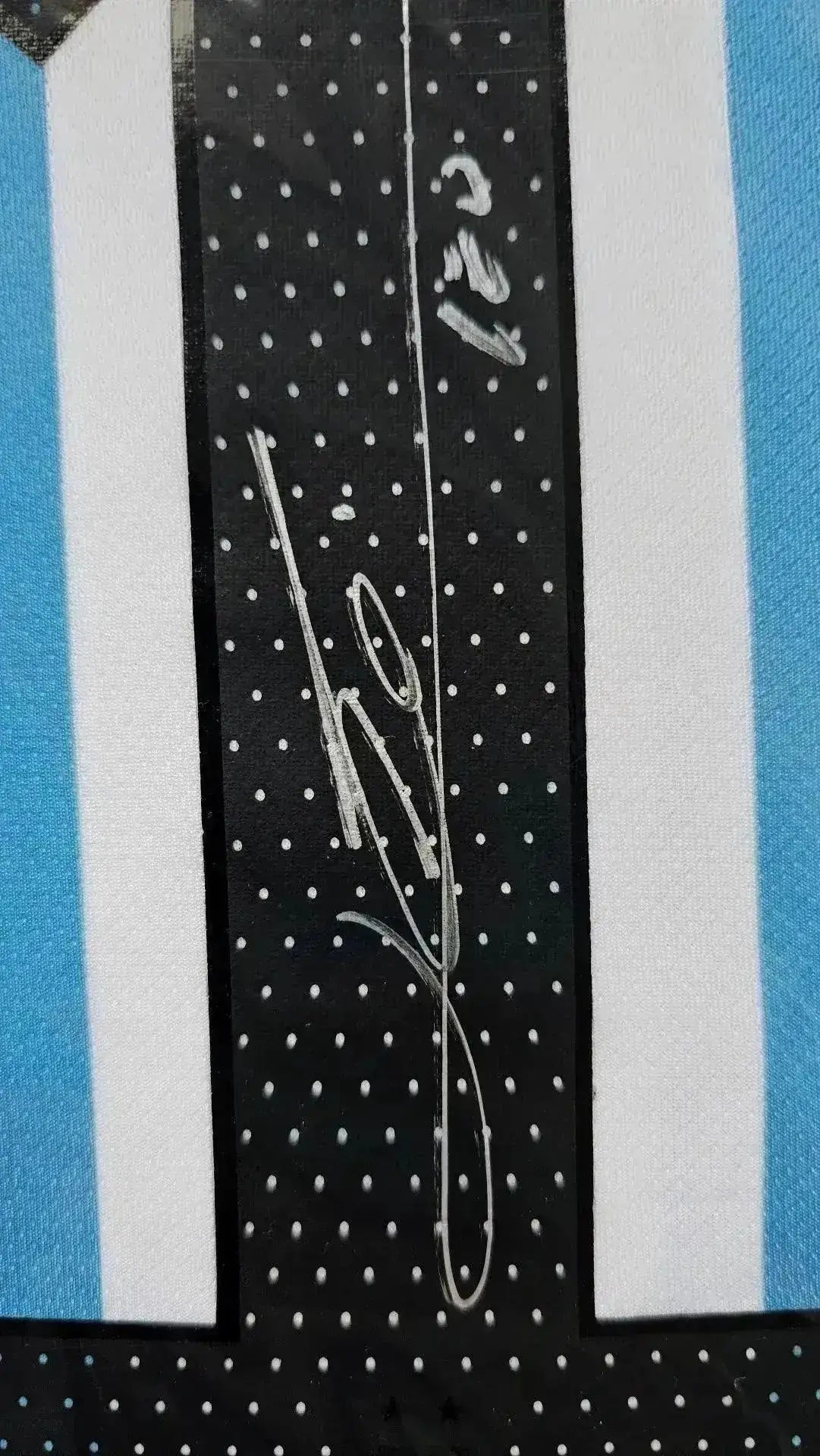 Close-up of signature detail on Lionel Messi 10 Argentina soccer jersey with white and blue stripes.