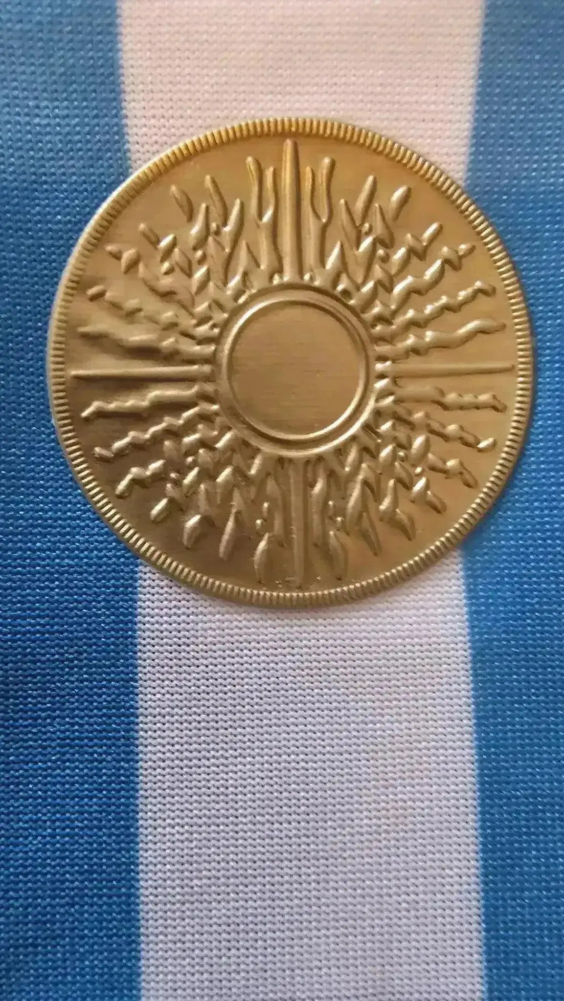 Detail of the gold emblem featuring the sun on the Argentina soccer jersey.