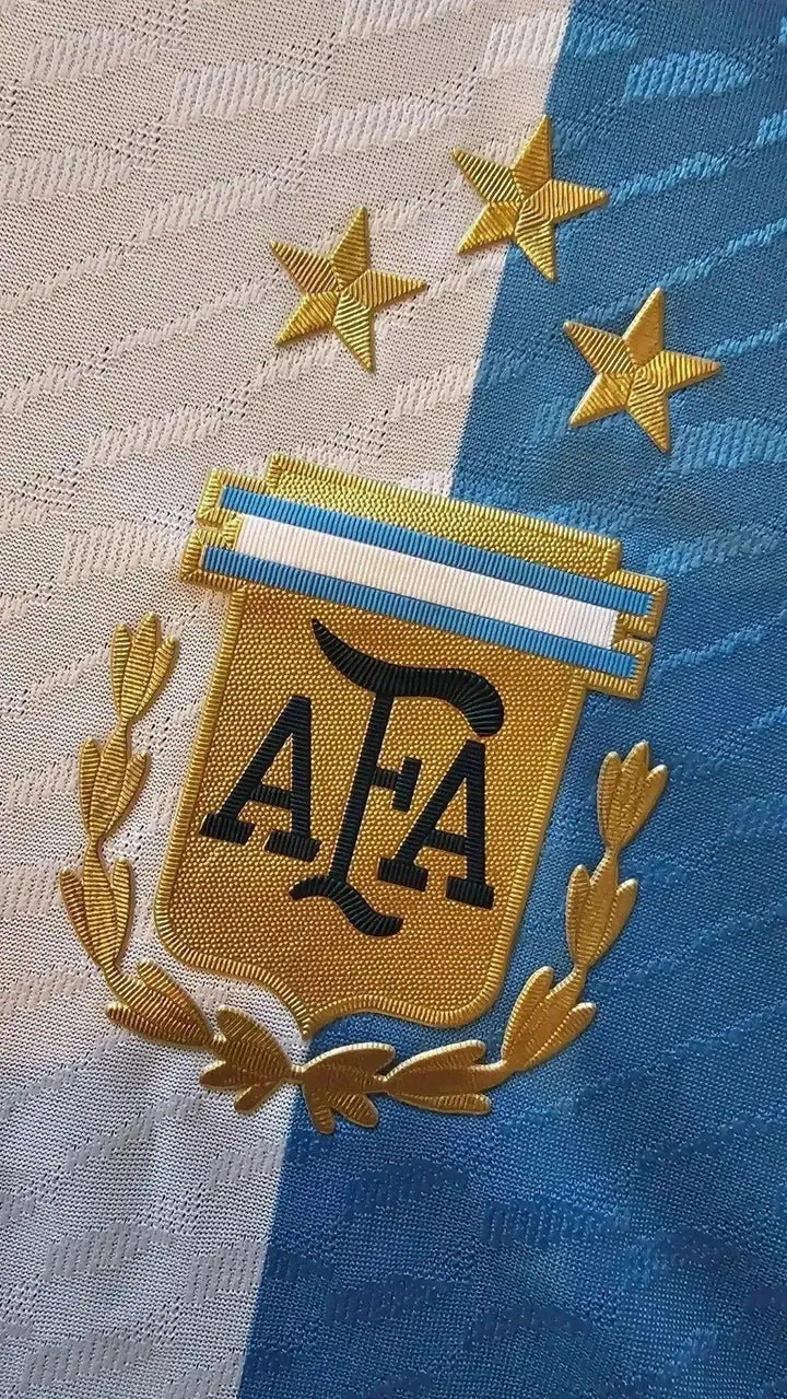 Detail view of the Argentina crest featuring three stars and AFA logo in gold embroidery.