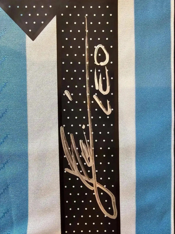 Signature detail of Lionel Messi in white on black area of the Argentina soccer jersey.