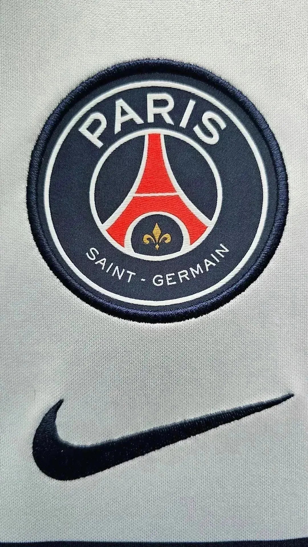 Crest detail of Paris Saint-Germain with visible "PARIS SAINT-GERMAIN" text and Nike logo.