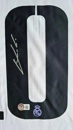 Detail showing signature and No. 10 on black and white Real Madrid soccer jersey.