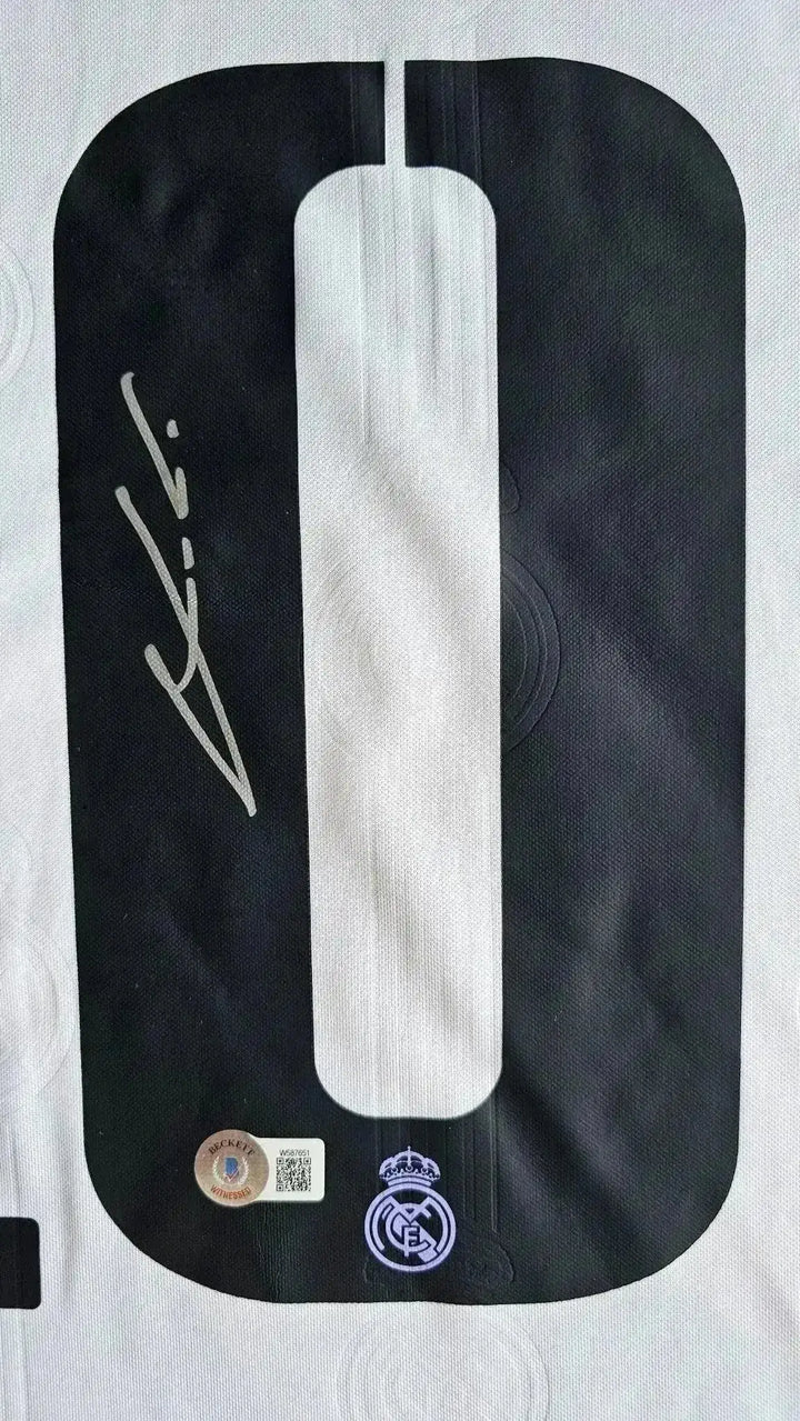 Detail showing signature and No. 10 on black and white Real Madrid football shirt.