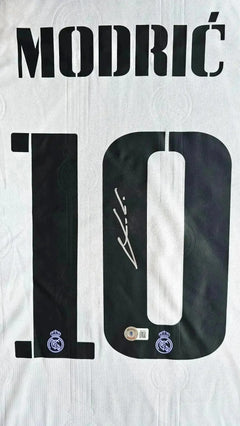 Detail view showing signature and No. 10 in black on a white Real Madrid soccer jersey.