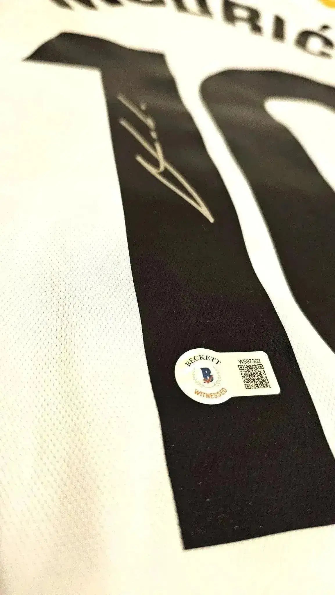 Detail view showing Luka Modrić signature and No. 10 on the black and white Real Madrid football shirt.