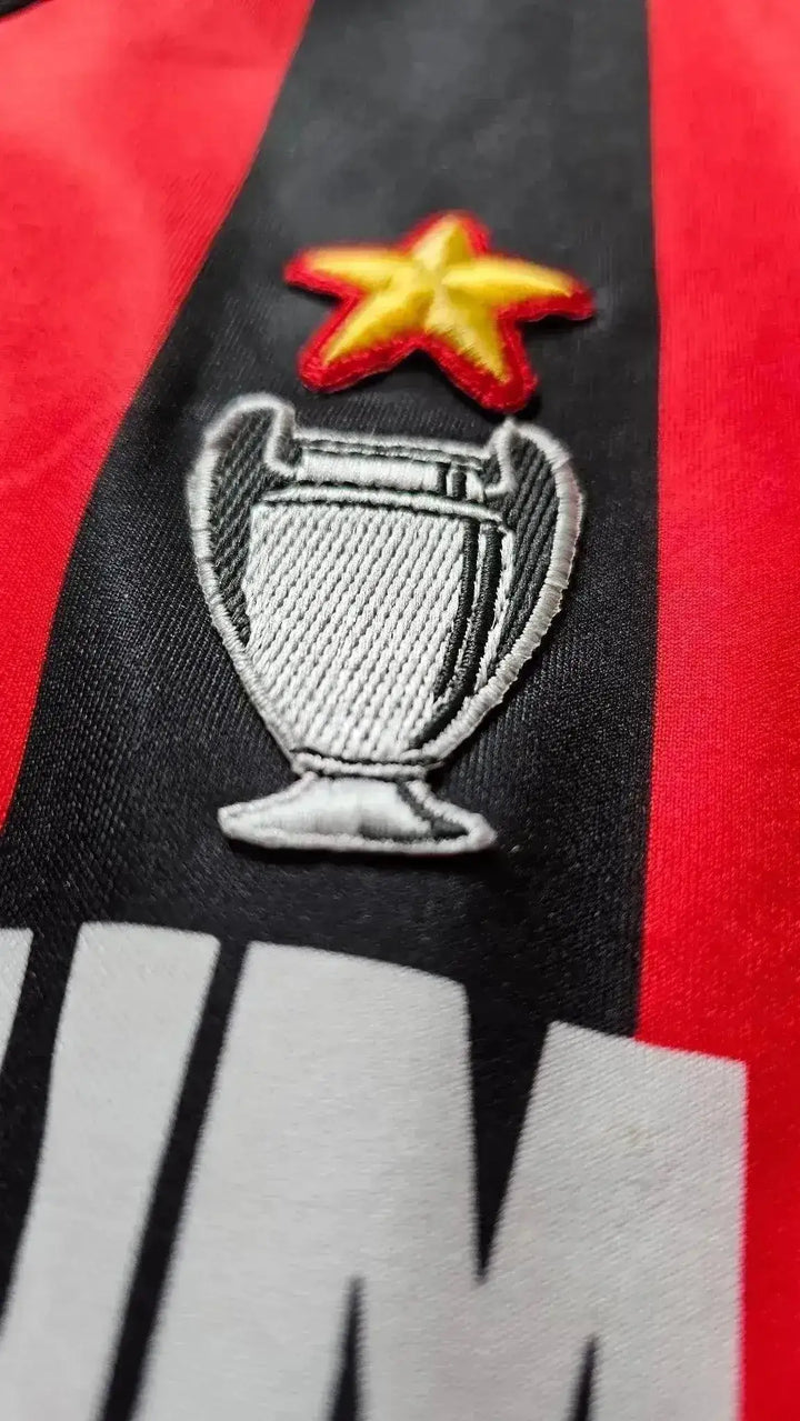 Crest detail showing UEFA Champions League trophy and star above on red and black background.
