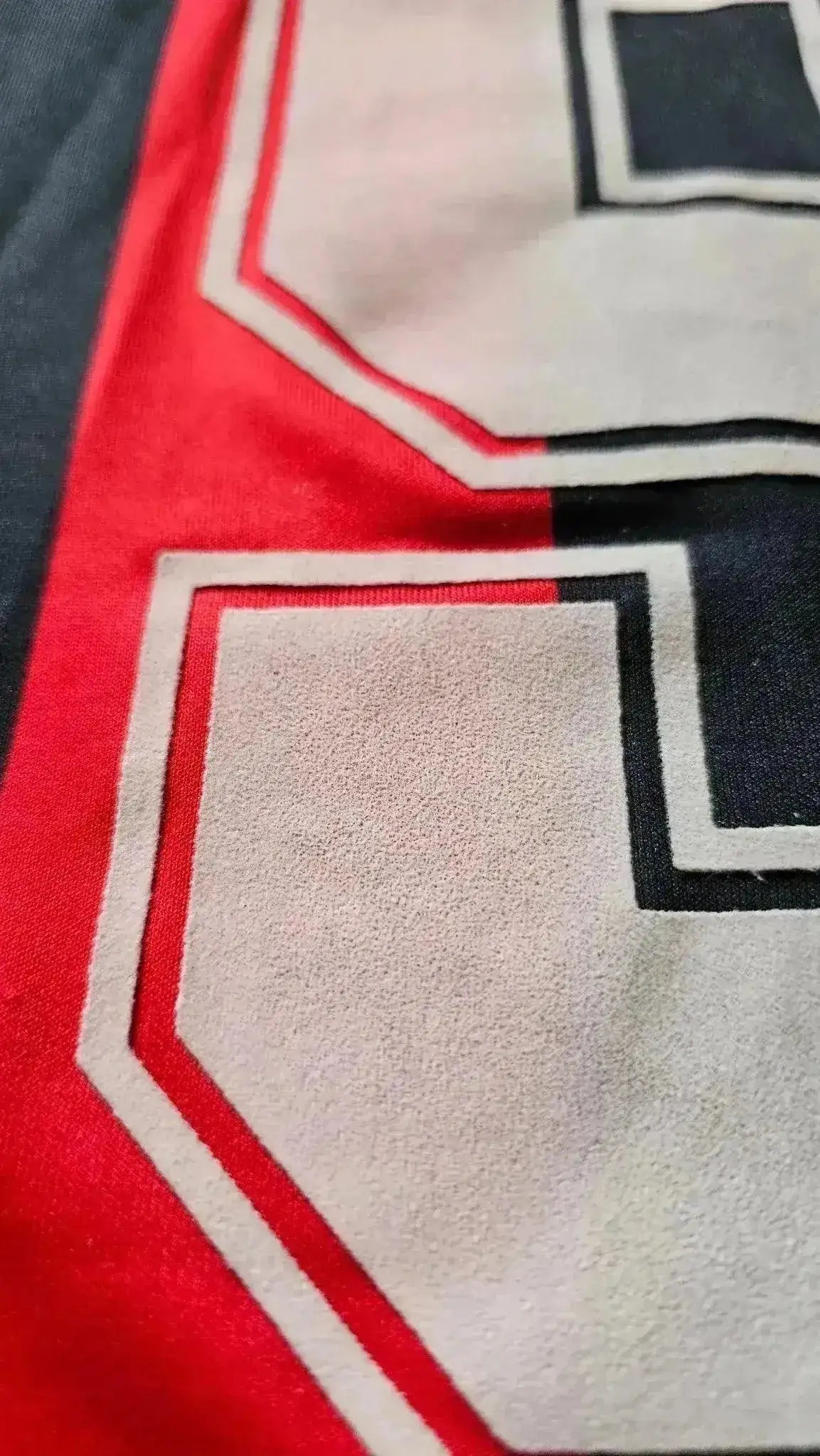 Detail view of the No. 9 on Marco van Basten's match-worn AC Milan football shirt, featuring red and black colors.