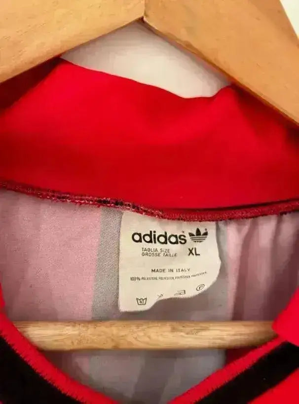 Adidas label showing size XL on the inside collar of a red and black football shirt.