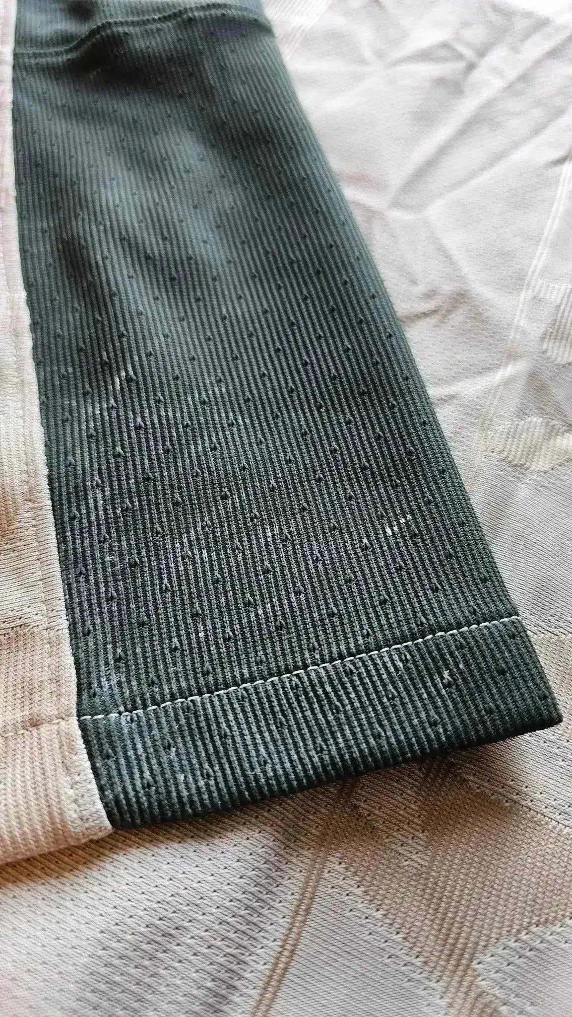 Close-up view of the dark green ribbed cuffs of a signed soccer jersey.