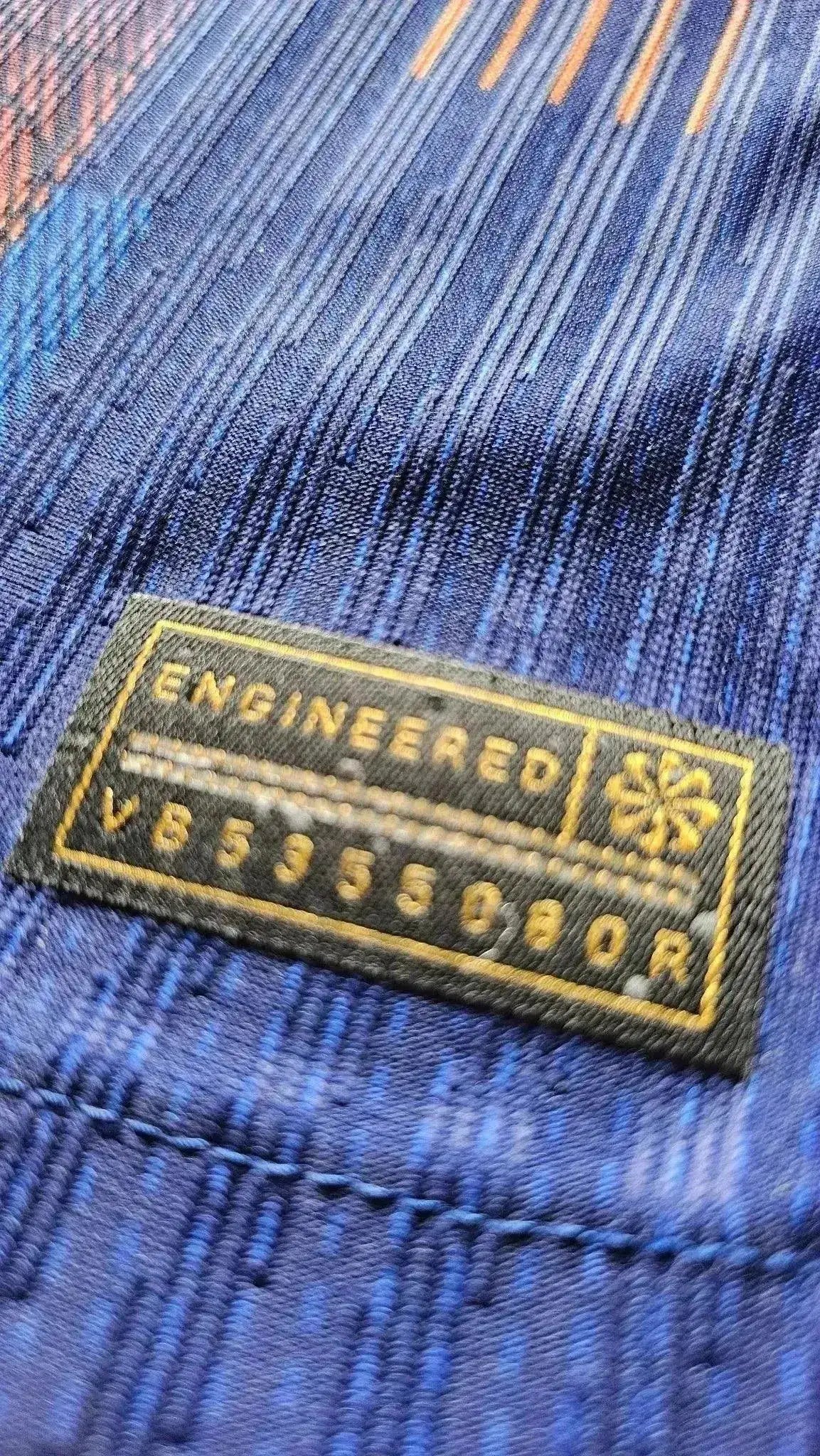 Close-up of the textile tag reading 'ENGINEERED V659550R' on the signed football shirt.