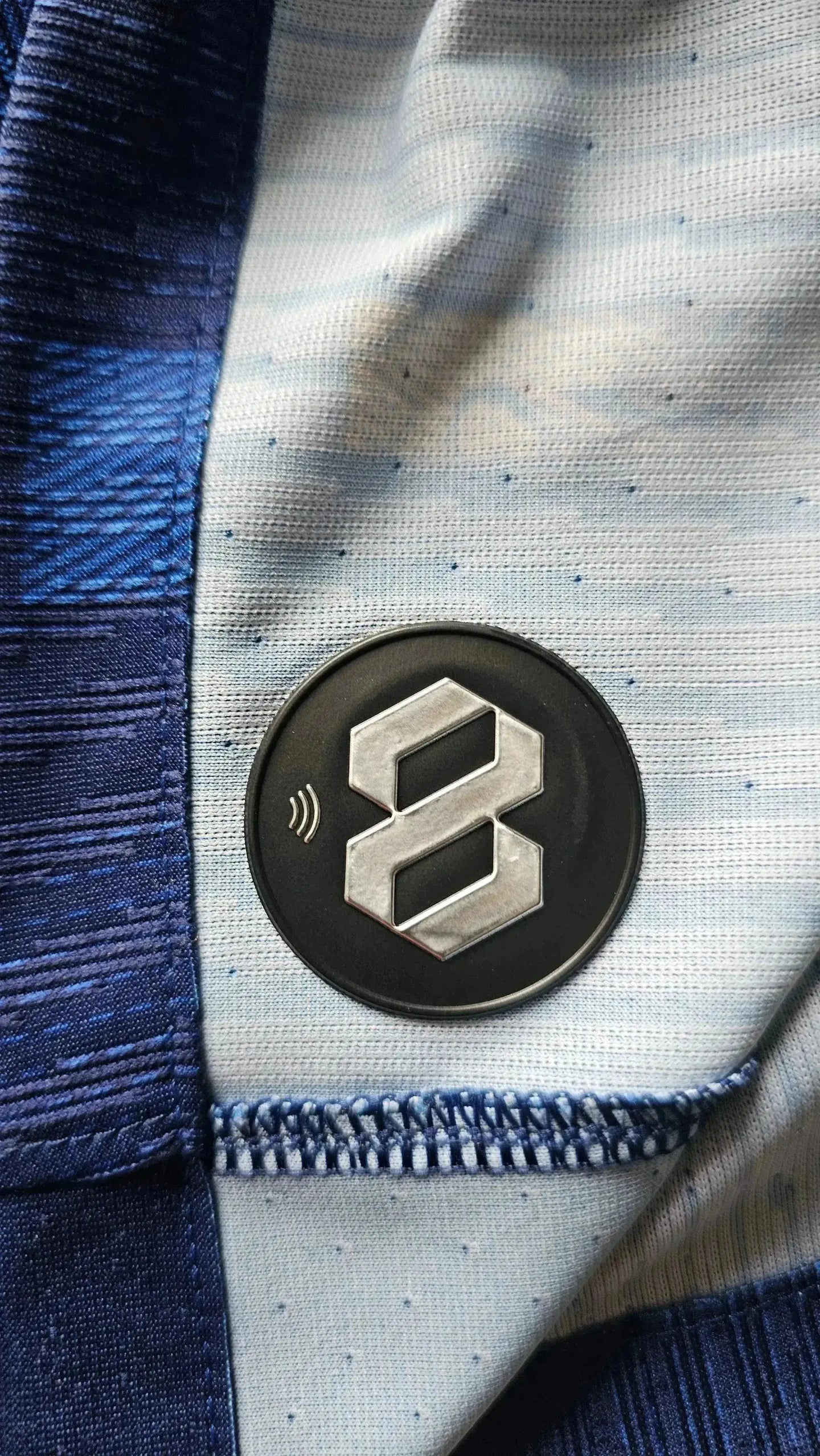 Crest detail showing 8 logo on fabric with blue and light blue background.