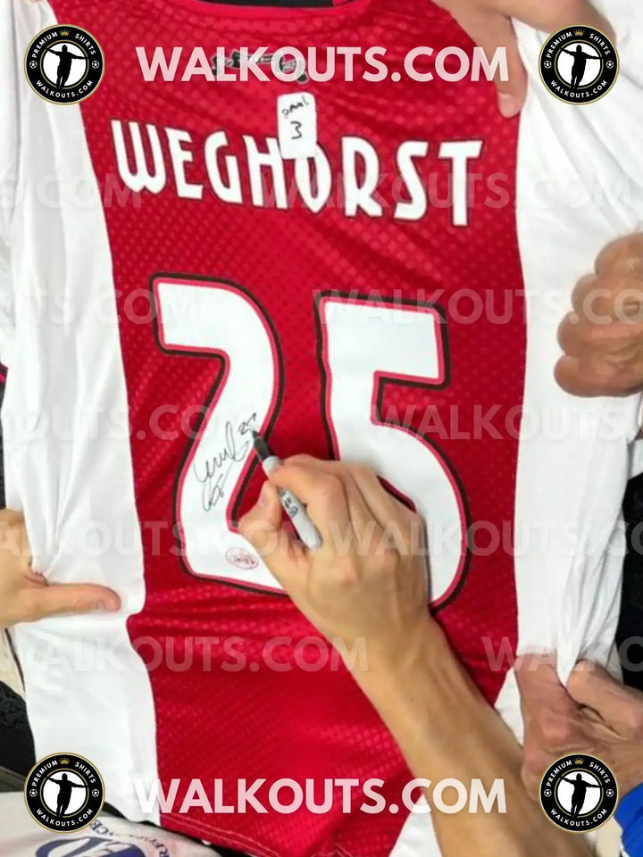 Wout Weghorst signing the red and white football shirt with No. 25 clearly visible.
