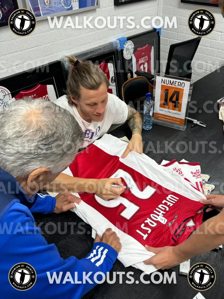 Wout Weghorst signs his red and white Ajax football shirt featuring No. 25.