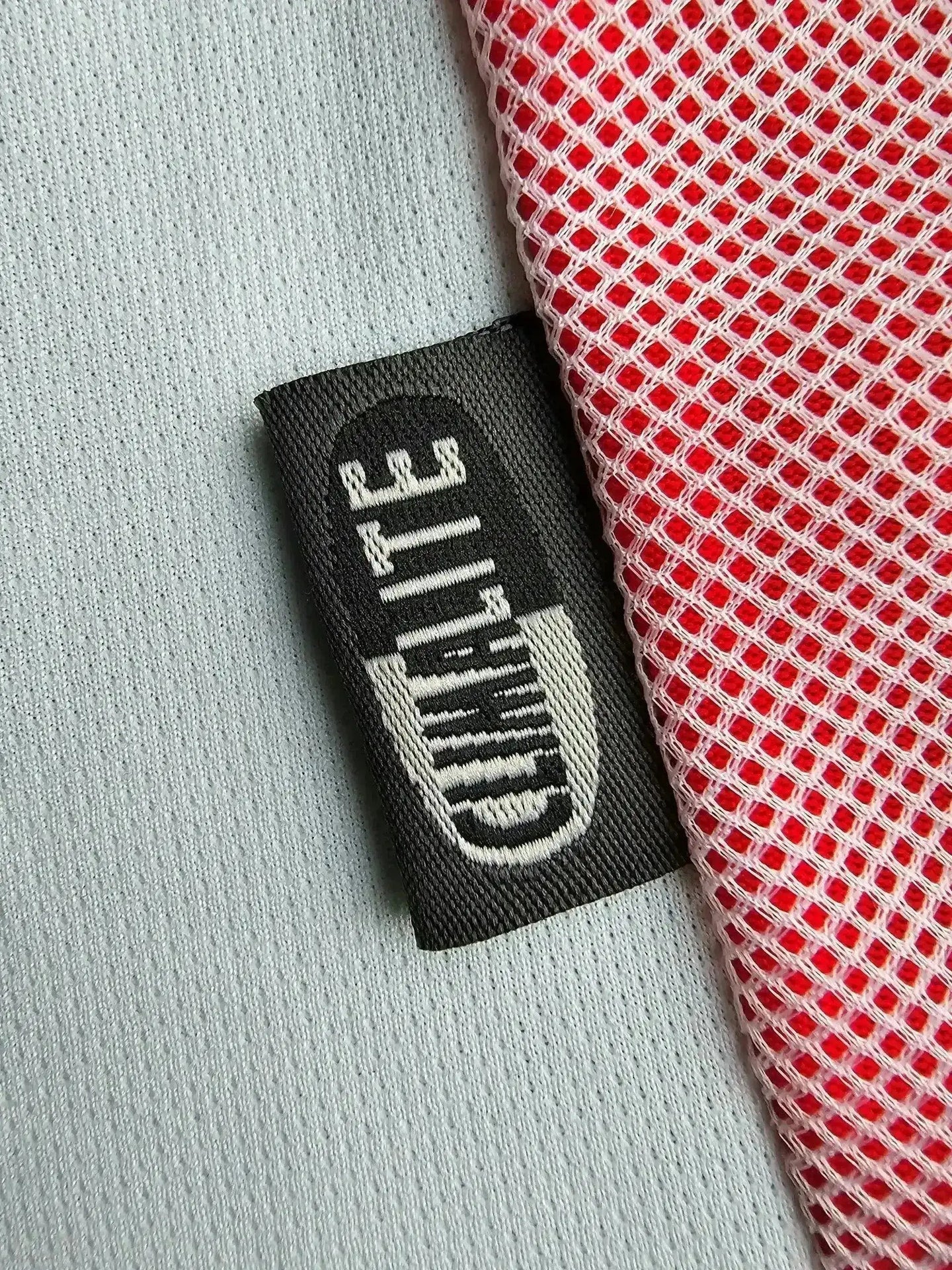Label detail featuring 'Quality' tag and red mesh fabric on the side of the soccer jersey.