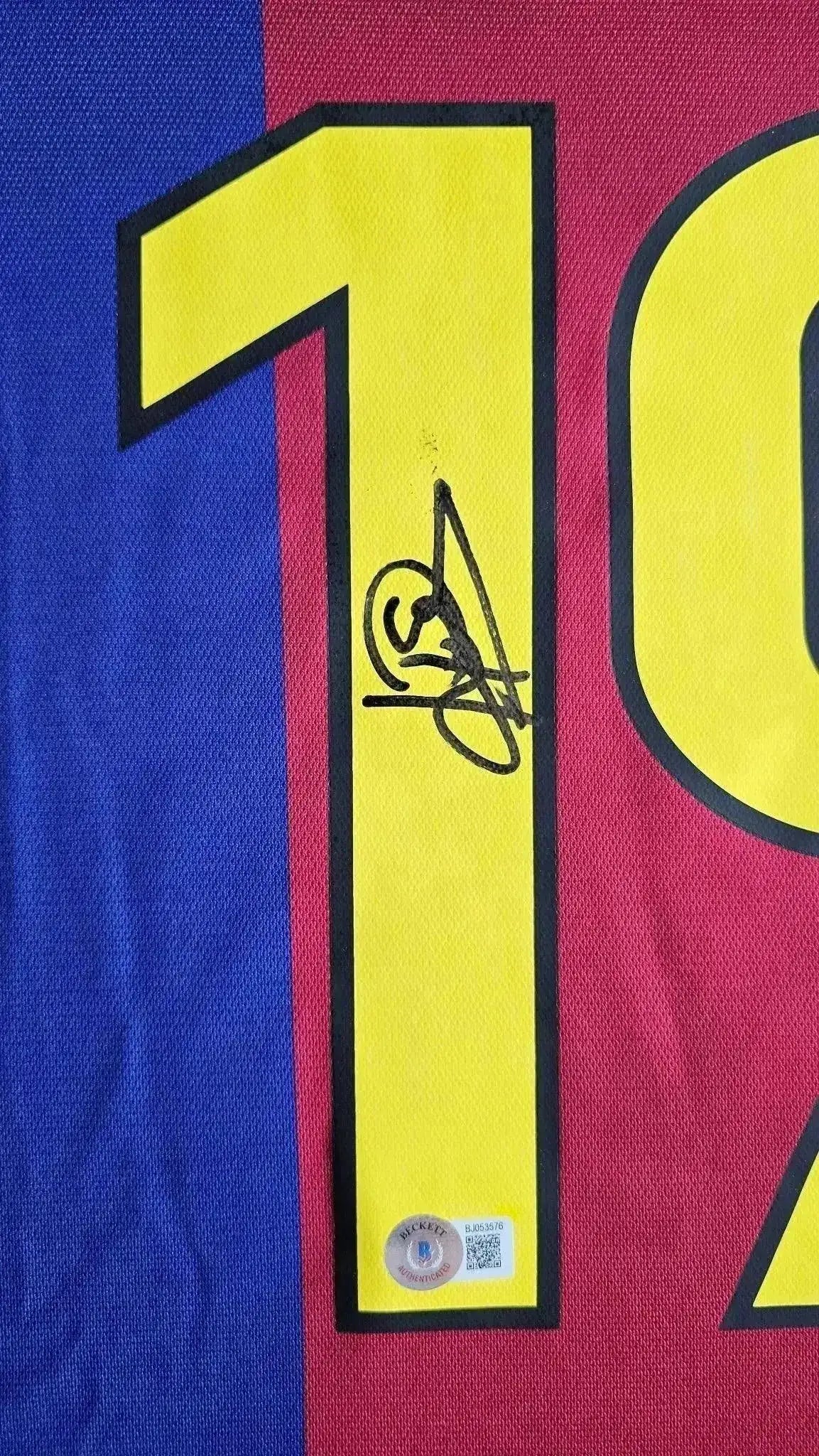Detail view of the No. 19 with Patrick Kluivert's signature on a Barcelona soccer jersey.