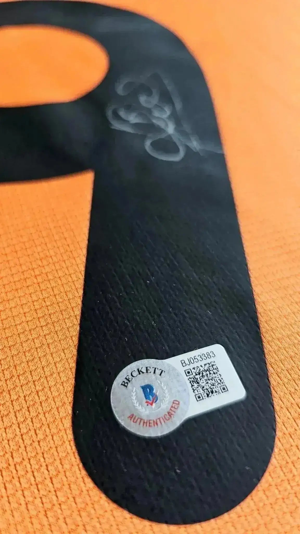 Signature detail on the No. 9 with Beckett authentication sticker visible. Orange background.