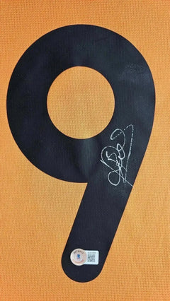 Close-up of No. 9 in black with signature on orange background and Beckett authentication sticker.