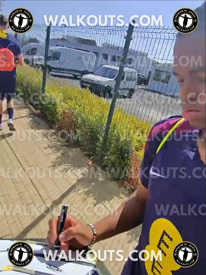 Rio Ngumoha signing a football shirt, visible Liverpool F.C. crest and sponsor logo.