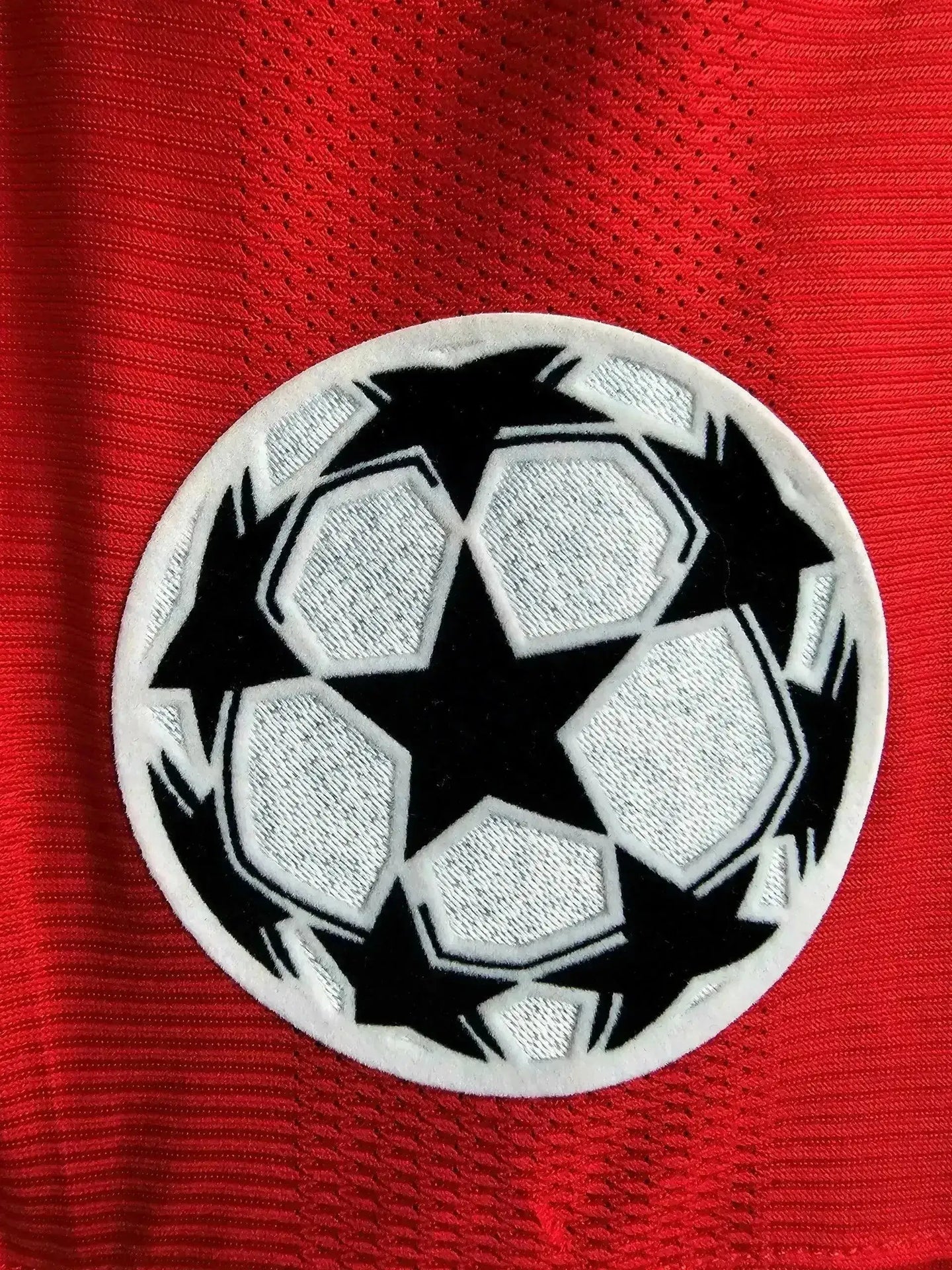 Detail view of the UEFA Champions League crest on a red background with white and black accents.