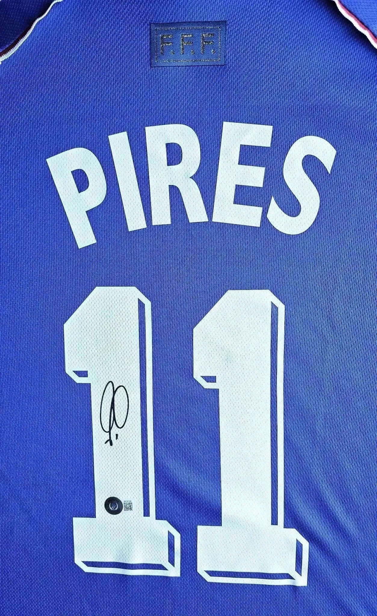 Back view showing Pirès, No. 11, and signature detail on blue France soccer jersey.