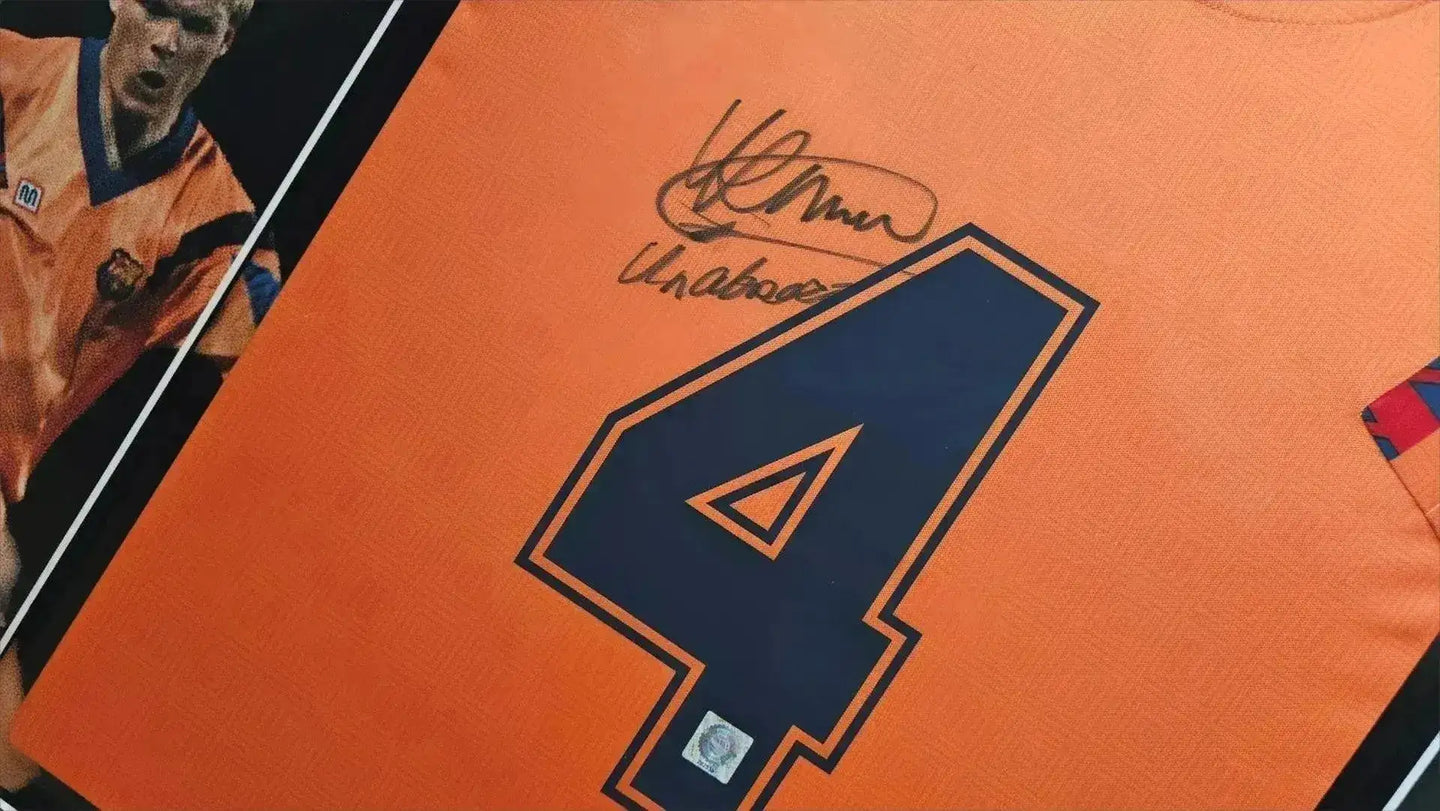 Signature detail featuring Ronald Koeman's autograph above the No. 4 on an orange football shirt.