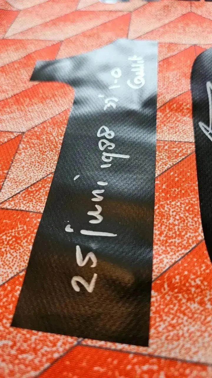 Detail view showing the signature of Ruud Gullit alongside match details on shirt sleeve.