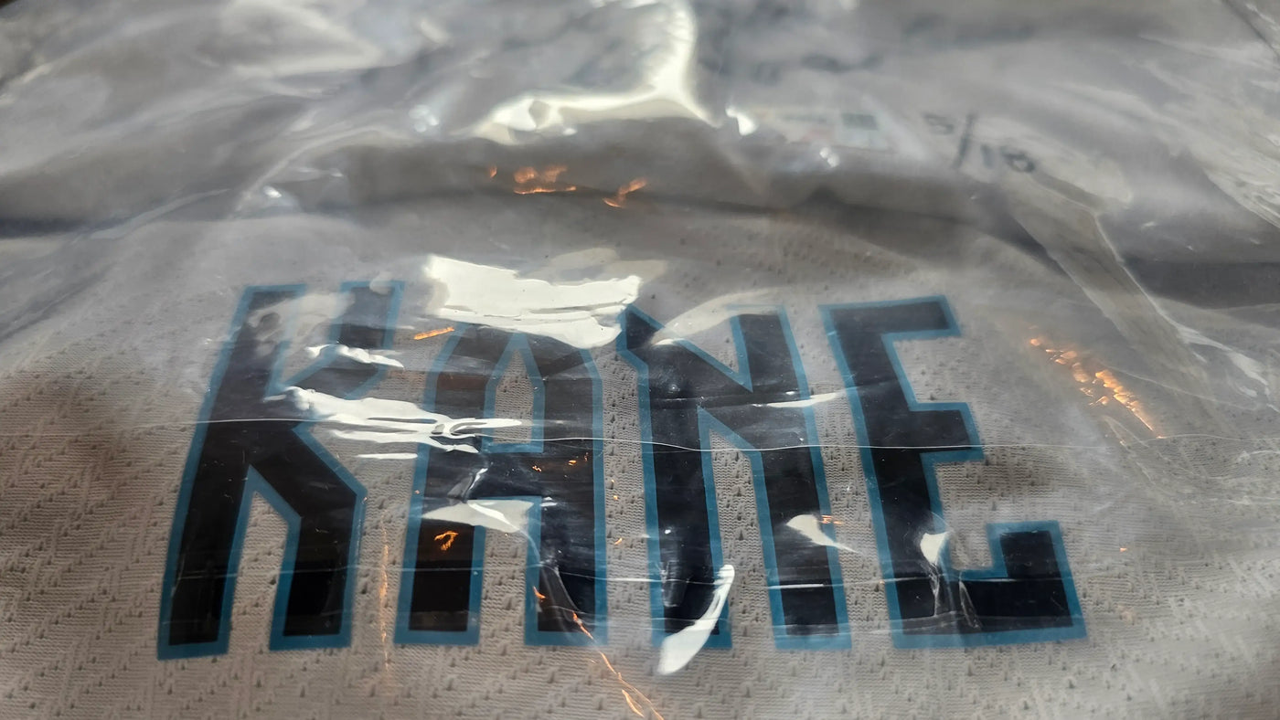 Sealed clear plastic bag with 'KANE' printed on it against a textured background.